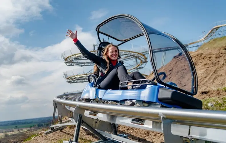 A woman waving from an alpine coaster sled