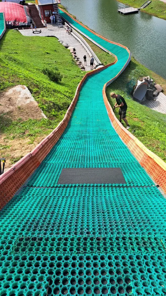 A long green tubing lane winding down a hillside, seen from the top
