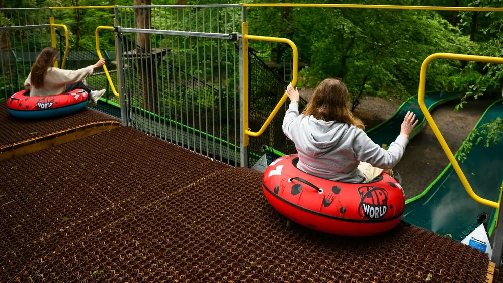 A rider in a red tube setting off from a starting platform with yellow handrails