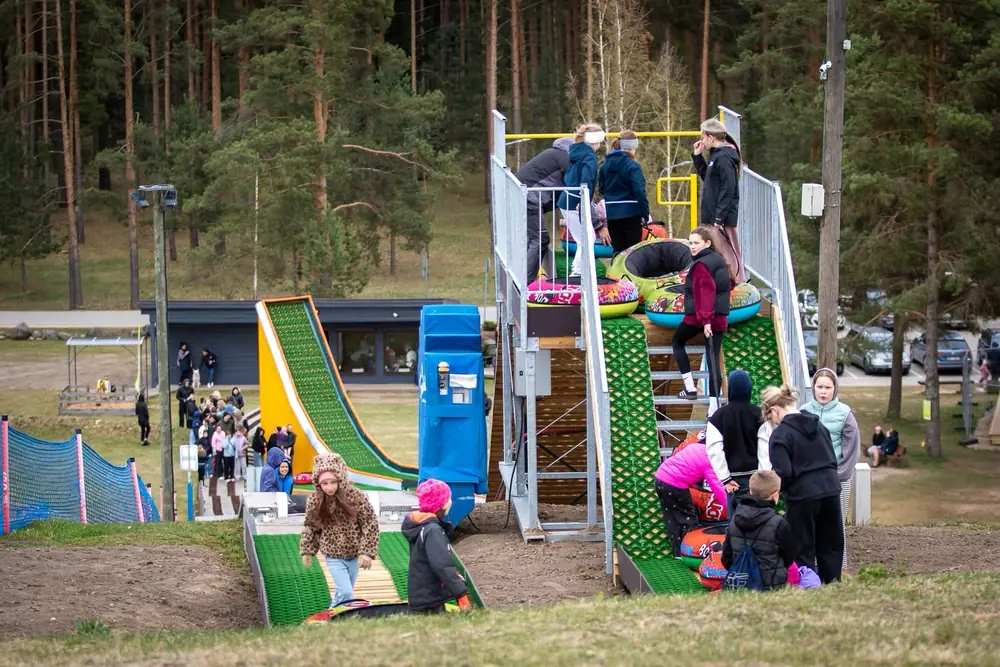 Families queueing on the stairs of a starting tower above twin tubing lanes