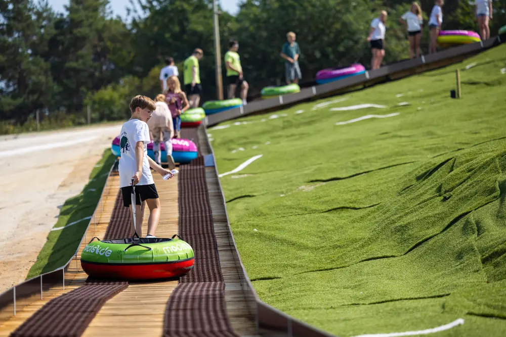 Riders pulling their tubes up a wooden walkway beside the Wijchen tubing slide