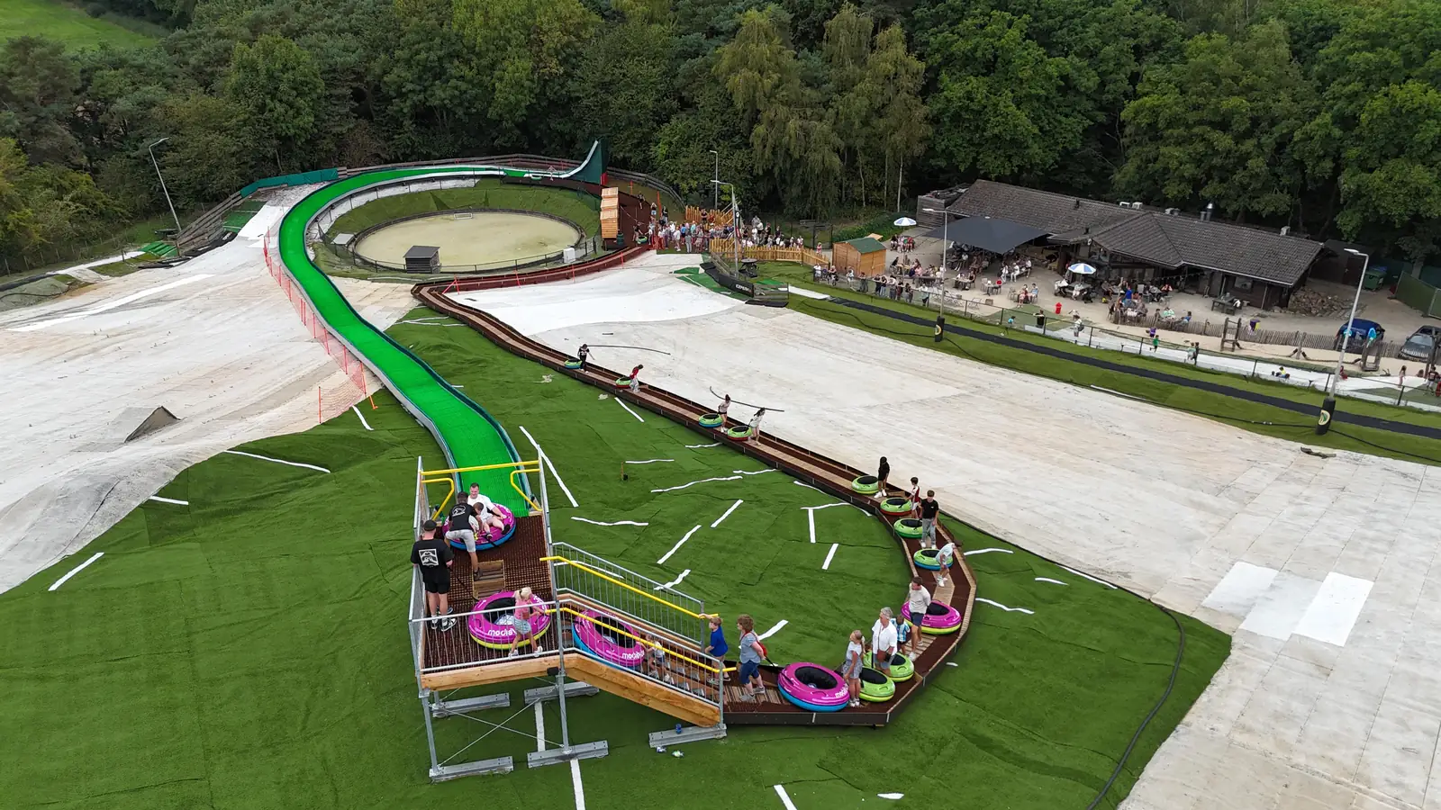 Aerial view of a tubing slide park: slide, start platform, tube return and visitor area