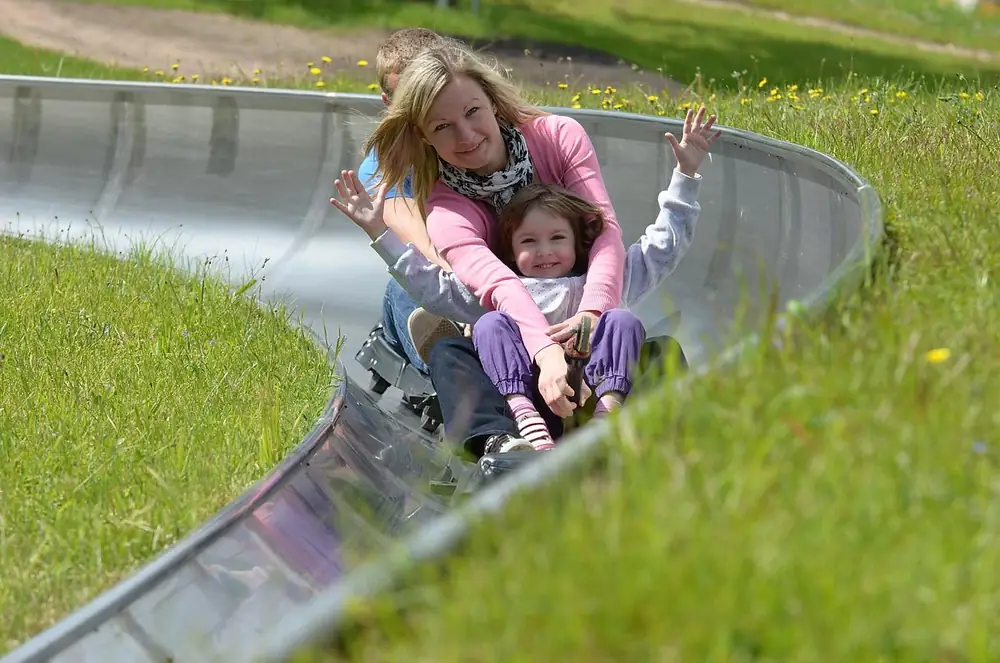A woman and a girl riding a curve of the Rāmkalni toboggan run